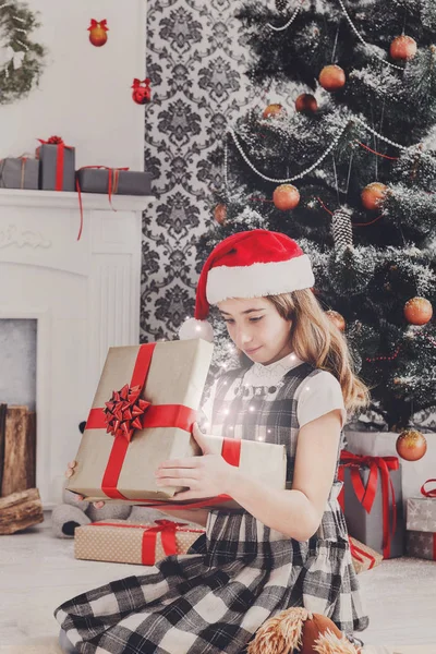 Bella ragazza in cappello di Babbo Natale scartando regali di Natale — Foto Stock