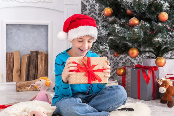 Süßer Junge mit Weihnachtsmütze beim Auspacken von Weihnachtsgeschenken — Stockfoto