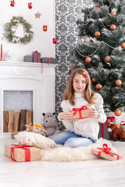 Hermosa chica en santa hat desenvolver regalos de Navidad —  Fotos de Stock