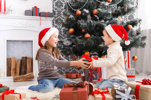 Enfants heureux dans chapeaux de Père Noël déballer cadeaux de Noël — Photo