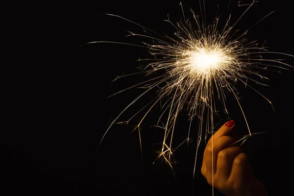 Fiesta de año nuevo sparkler en mano femenina sobre fondo negro — Foto de Stock