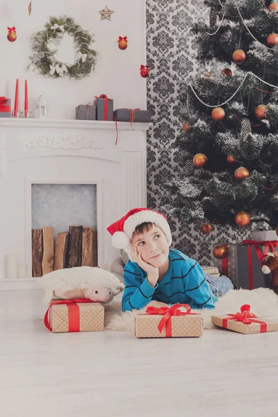 Lindo chico en sombrero de santa y regalos de Navidad —  Fotos de Stock