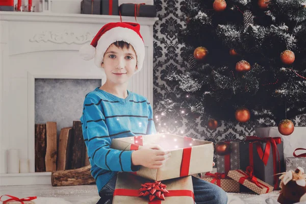 Милий щасливий хлопчик у капелюсі Санта, який не завантажує різдвяні подарунки — стокове фото