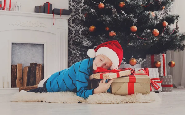 Süßer Junge mit Weihnachtsmütze beim Auspacken von Weihnachtsgeschenken — Stockfoto