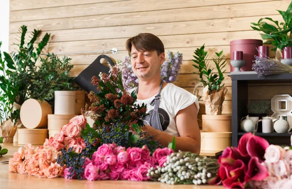 Hombre florista asistente en la entrega de la tienda de flores hacer ramo de rosas —  Fotos de Stock