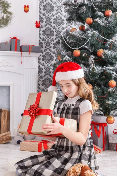 Schönes Mädchen mit Weihnachtsmütze beim Auspacken von Weihnachtsgeschenken — Stockfoto