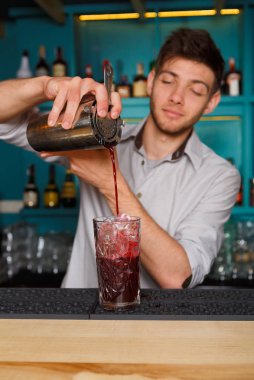 Genç yakışıklı barmen kokteyl içki cam içine dökme