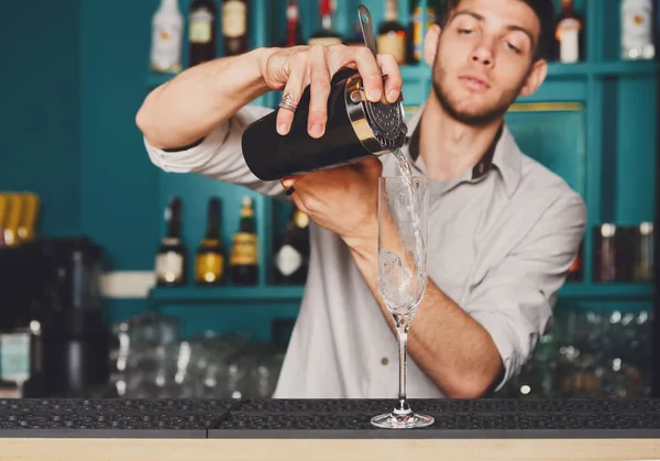 Joven barman guapo vertiendo bebida de cóctel en el vaso — Foto de Stock