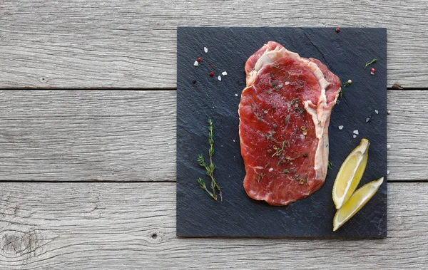 Rauwe biefstuk op donkere houten tafel achtergrond, bovenaanzicht — Stockfoto