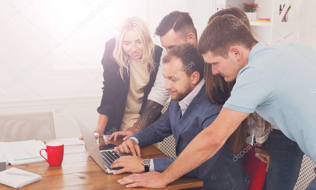 Happy business people team together look at laptop in office