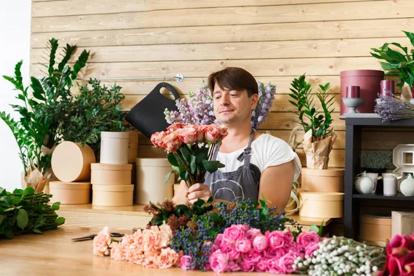 Man florist assistant in flower shop delivery make rose bouquet