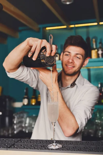 Joven barman guapo vertiendo bebida de cóctel en el vaso — Foto de Stock