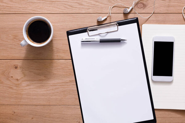 Офисные принадлежности и мобильный телефон на деревянном фоне
