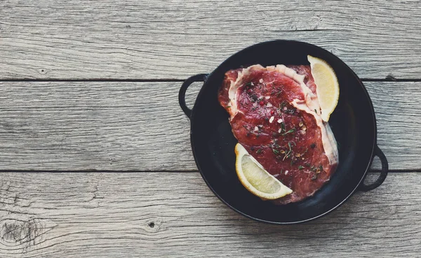 Steak de boeuf cru sur fond de table en bois foncé, vue de dessus — Photo