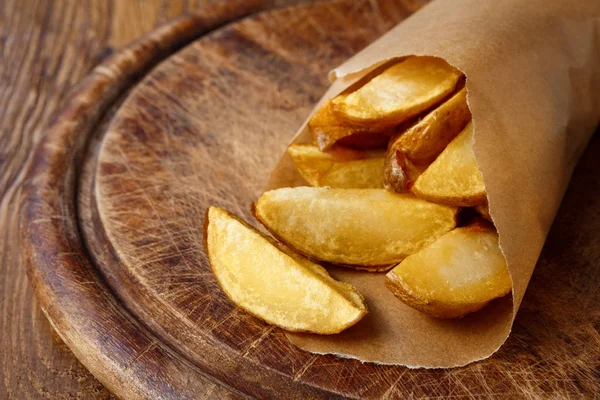 Fries and potato wedges wrapped takeaway at wood