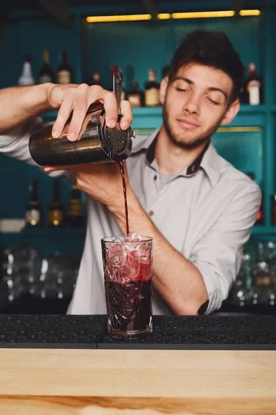 Joven barman guapo vertiendo bebida de cóctel en el vaso — Foto de Stock
