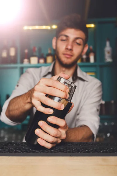 Joven barman guapo en el bar sacudiendo y mezclando cóctel de alcohol — Foto de Stock