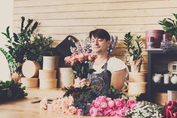 Homem assistente na entrega loja de flores fazer buquê de rosa — Fotografia de Stock
