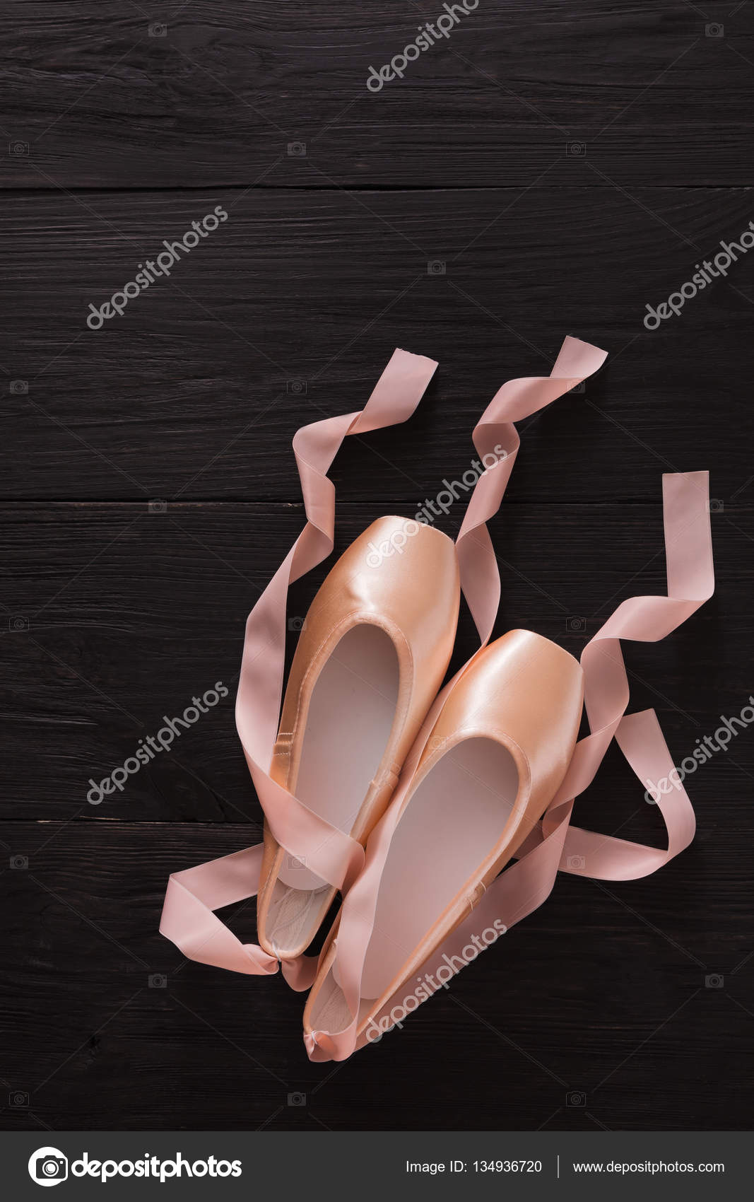 Zapatillas puntas de ballet rosa sobre fondo de madera negra