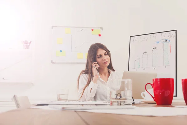 Hermosa joven empresaria sentada junto al escritorio de la oficina con computadora portátil — Foto de Stock