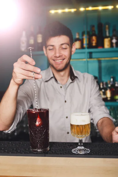 Joven barman guapo vertiendo bebida de cóctel en el vaso — Foto de Stock