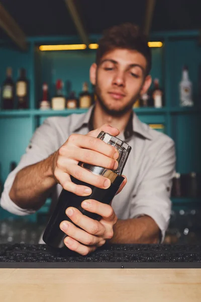 Jovem barman bonito no bar tremendo e misturando coquetel de álcool — Fotografia de Stock