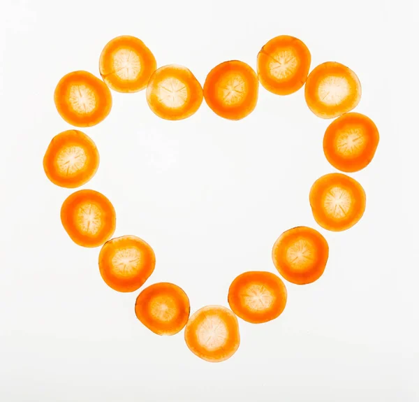 Fette retroilluminate di carota a forma di cuore, sfondo strutturato astratto — Foto Stock