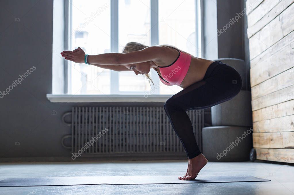 Young woman in yoga class, vinyasa transition to pose
