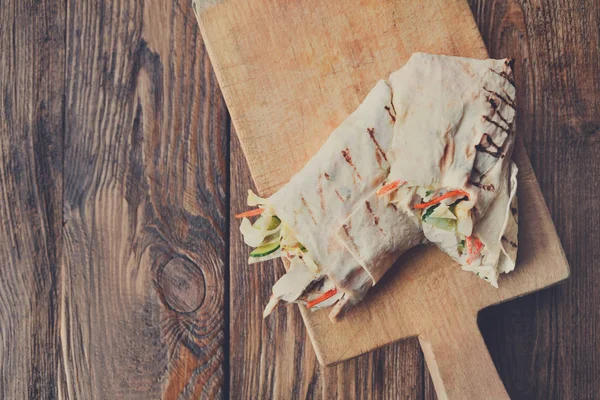 Burrito med fläskkött och grönsaker på trä skrivbord — Stockfoto