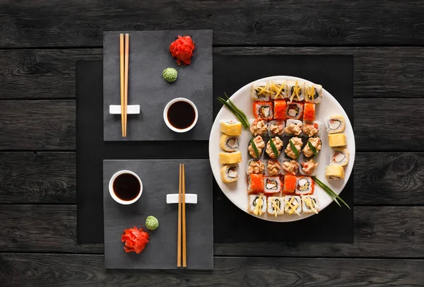 Sada sushi maki a rohlíky na černé rustikální dřevo, horní pohled — Stock fotografie