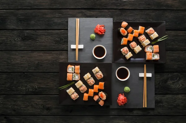 Set sushi maki en broodjes op zwarte rustieke houten, top uitzicht — Stockfoto