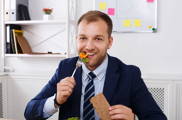 Man has healthy business lunch in modern office interior