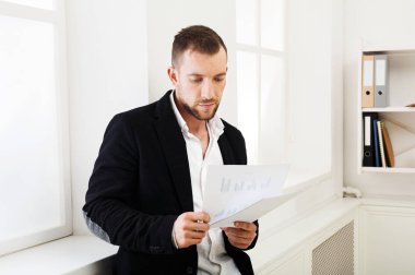 Genç işadamı okuma modern beyaz office belgelerinde konsantre