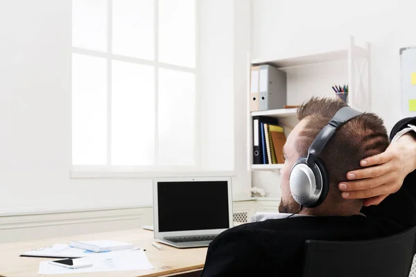 Over schouder luisteren schot van zakenman in kantoor muziek in hoofdtelefoons — Stockfoto