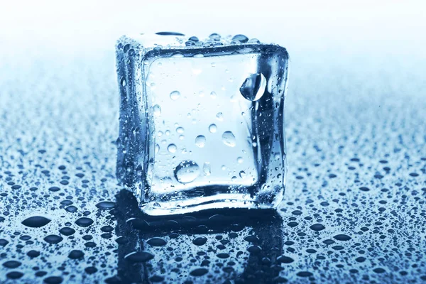 Glaçon transparent avec réflexion sur verre bleu avec gouttes d'eau — Photo