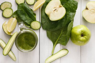 Beyaz ahşap zemin üzerinde doğal detoks yeşil smoothie maddeler