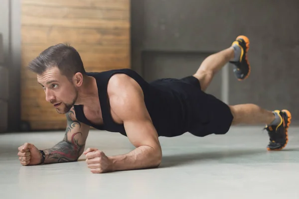 Jongeman fitnesstraining, verhoogde been plank — Stockfoto