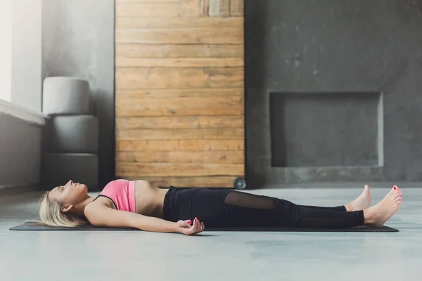 Young woman in yoga class, relax meditation corpse pose
