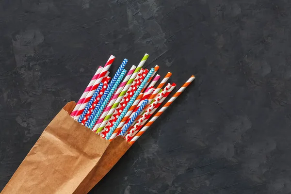 Colorful striped cocktail straws in craft package on blackboard background — Stock Photo, Image