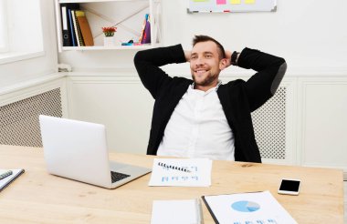 Genç işadamı modern beyaz ofis içinde laptop ile rahat