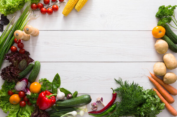 Border of fresh vegetables on white wood background with copy space