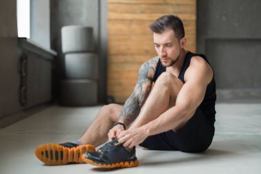 Yakışıklı genç dantel ayakkabı eğitimden sonra spor salonunda