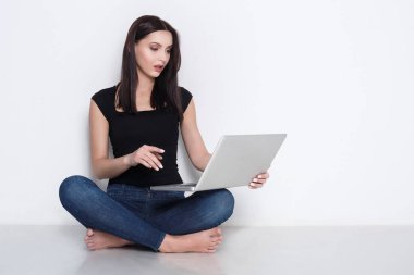Stüdyo katta oturan dizüstü kullanan kadın