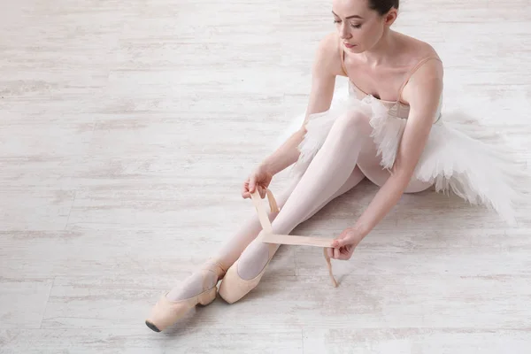 Bailarina se pone zapatos de ballet puntiagudos, piernas elegantes —  Fotos de Stock