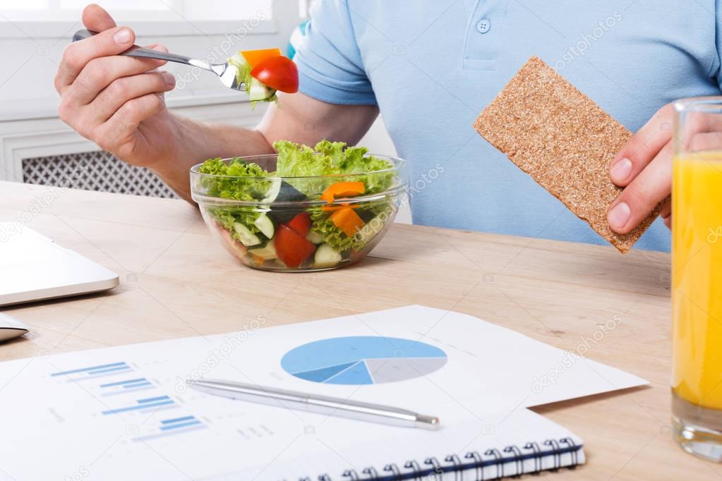 Unrecognizable man has healthy business lunch in modern office interior