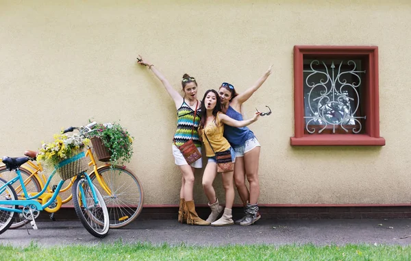 Felice boho chic ragazze posare con biciclette vicino alla facciata della casa — Foto Stock