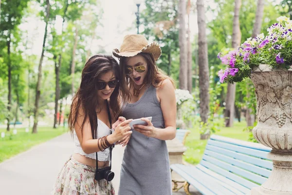 Outdoor portrait of two friends watching photos with a smartphone — Stock Photo, Image