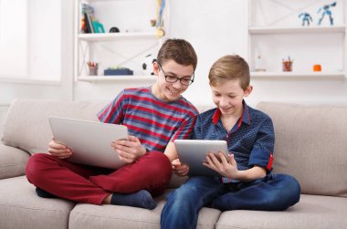Tablet kullanarak iki genç erkek evde kanepe