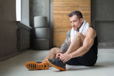 Yakışıklı genç dantel ayakkabı eğitimden sonra spor salonunda