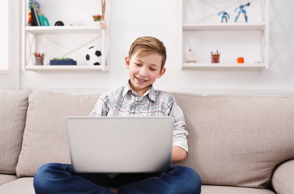 Tonårspojke med laptop på soffan hemma — Stockfoto
